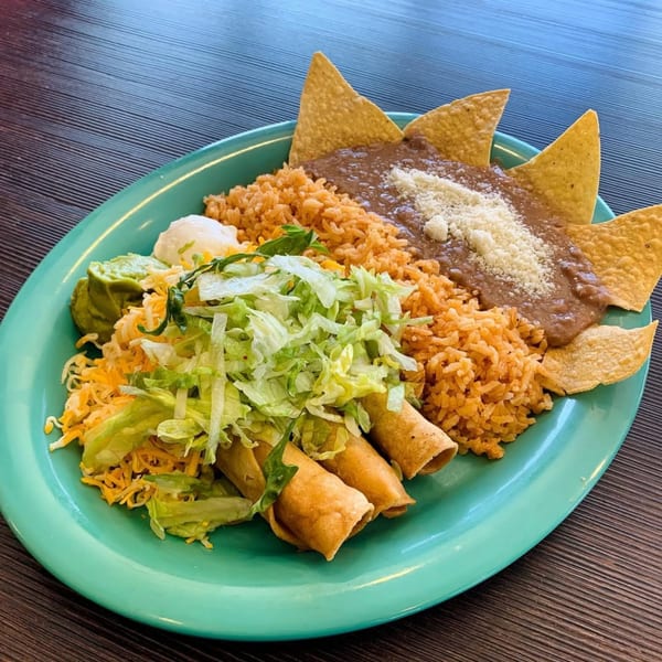 Chilitos Mexican Grill's combination plate with taquitos, rice, beans, guacamole, sour cream, cheese, and lettuce.