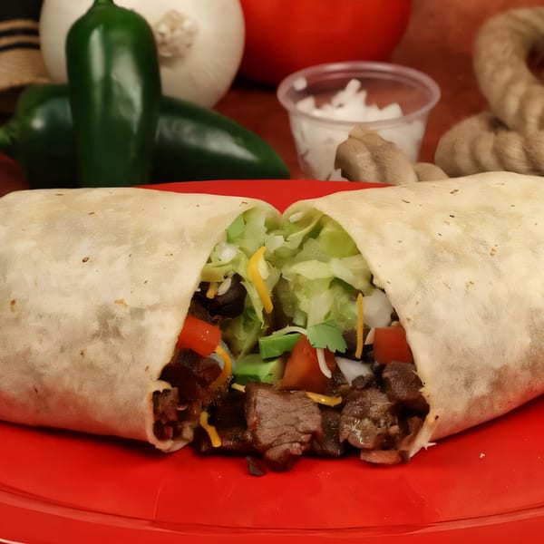 A Chilitos Mexican Grill burrito, cut in half, revealing steak, lettuce, cheese, and tomatoes on a red plate.